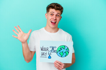 Young caucasian man holding a water day placard isolated on blue background