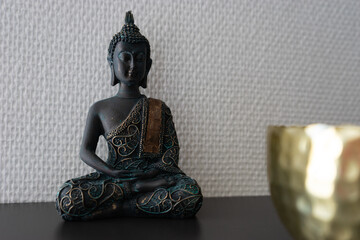 Buddha statue inside house in front of a white wall.