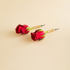 Creative arrangement with red flowers as darts on a beige background. Minimal nature or game...