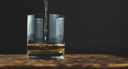 glass of whiskey with ice on the wooden table