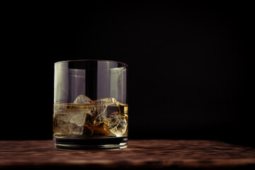 glass of whiskey with ice on the wooden table