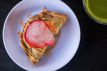 Deep-fried, hard-shell crab taco topped with salsa, slaw, and radish on a white plate. This dish is served at a beach restaurant in the Riviera Nayarit in Mexico.