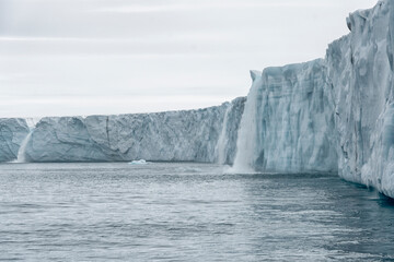 Fototapeta na wymiar Svalbard, Nordaustlandet Island. Waterfalls cascade from the melting glacier.