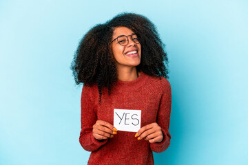 Young african american curly woman holding a yes placard laughing and having fun.