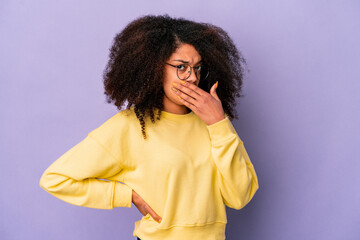 Young african american curly woman isolated on purple background covering mouth with hands looking worried.