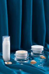 beauty mineral moisturizer cream, shells, sea â€‹â€‹salt  in glass jar, blue background...