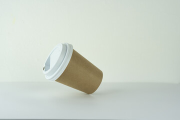 a takeaway paper cup is falling on a white table.