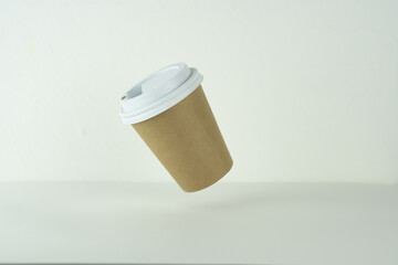 a takeaway paper cup is falling on a white table.