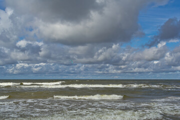Beach during the day. Clouds and sea waves.