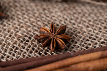 cinnamon sticks and badian lie against the background of sackcloth.