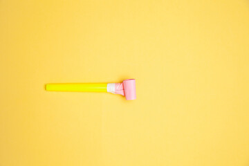 Party horn and scattered shiny confetti on orange background