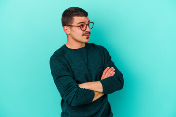 Young caucasian man isolated on blue background dreaming of achieving goals and purposes