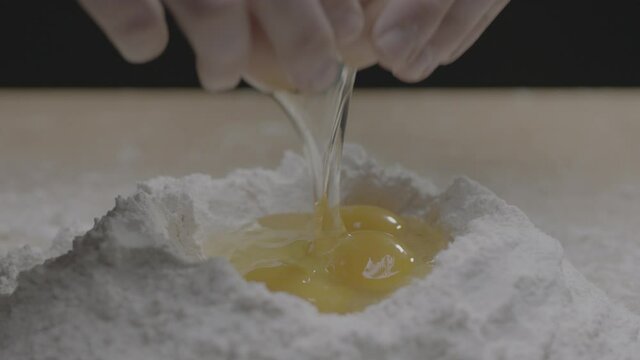 A third egg is cracked into flour bowl