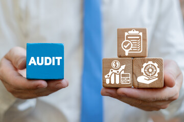 Finance and business concept of audit. Auditor holding wooden cubes with audit conceptual icons.