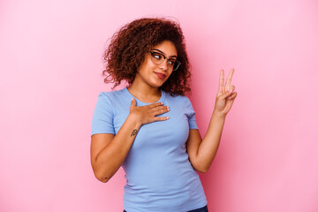 Young african american woman isolated on pink background taking an oath, putting hand on chest.