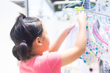 kid helper at home.Laundry in summer morning at home.Asian girl child line dry the clothes with her mother.kid activity during lockdown covid19 coronavirus. hygiene clean and dry cloth.responsibility.