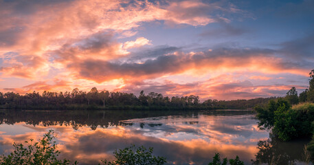 Fototapeta premium Panoramic Riverside Sunrise with Dramatic Cloud Reflections