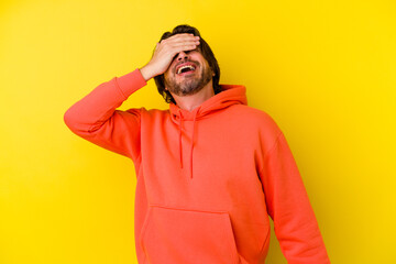 Middle age caucasian man isolated on yellow background covers eyes with hands, smiles broadly waiting for a surprise.