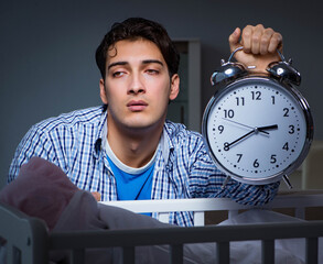 Young father dad sleeping while looking after newborn baby