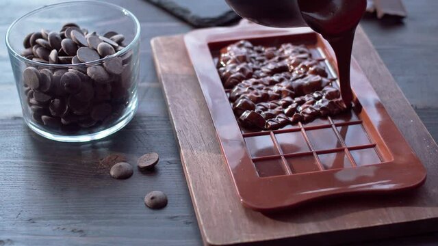 Homemade pouring chocolate into bar mold silicone and chocolate callets on table