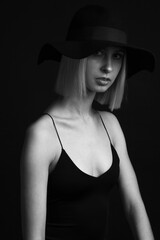 Black and white portrait blondes on a black background in a hat and Tank Top With Thin Straps.