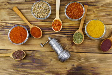 Set of different aromatic spices and spice mill on wooden table. Top view