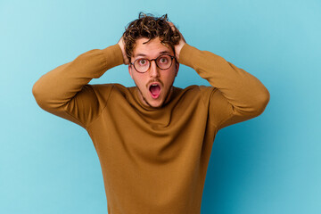 Young caucasian man wearing eyeglasses isolated on blue background screaming, very excited, passionate, satisfied with something.