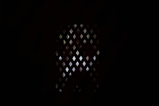 view of a confessional grille in the darkness of a church