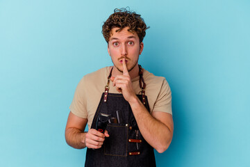 Young barber caucasian man isolated on blue background keeping a secret or asking for silence.