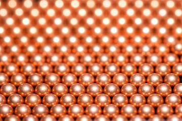 Close-up view of aligned copper balls with selective background and shiny bokeh background