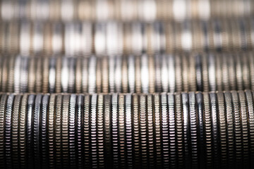 Full-screen background of horizontal stacks of silver metal coins with a ribbed edge, selective...