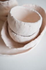 Clay dishes on a white table. Handmade cups and plates