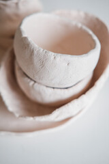 Clay dishes on a white table. Handmade cups and plates