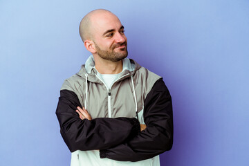 Young caucasian bald man isolated on purple background dreaming of achieving goals and purposes