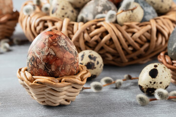 Easter composition - several marble eggs painted with natural dyes in a wicker nest and baskets