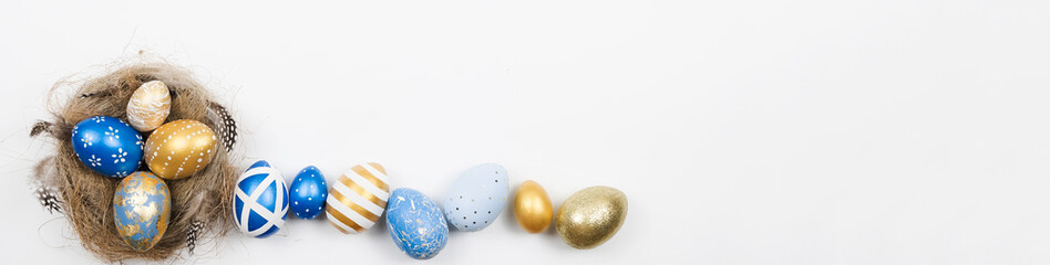 Easter golden blue decorated eggs in nest isolated on white background for web banner. Minimal easter concept. Happy Easter card with copy space for text. Top view, flatlay.