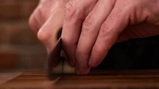 Fastly chopping garlic cloves on a wooden board.