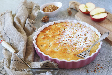 Apple clafoutis pie with praline in ceramic dish for sweet dessert and fresh apples