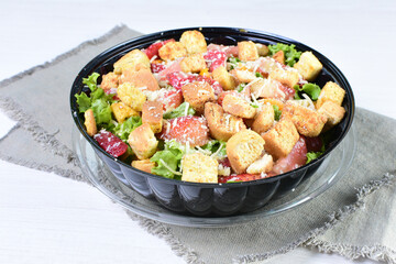 Rich very colorful vegetable salad, with croutons, strawberries, lettuce, Parmesan cheese and cherry tomato on white wooden background