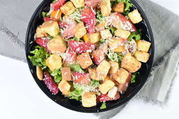 Rich very colorful vegetable salad, with croutons, strawberries, lettuce, Parmesan cheese and cherry tomato on white wooden background