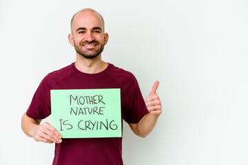 Young caucasian bald man holding a Mother Nature crying isolated on white background smiling and...