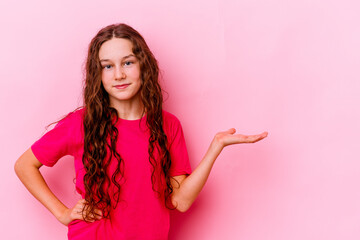 Little caucasian girl isolated on pink background showing a copy space on a palm and holding...