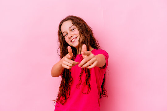 Little caucasian girl isolated on pink background cheerful smiles pointing to front.