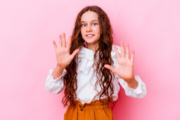 Little caucasian girl isolated on pink background rejecting someone showing a gesture of disgust.