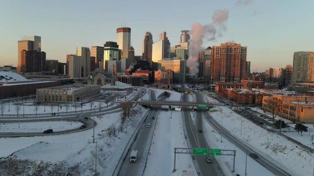 downtown minneapolis seen from the south side during a winter polar vortex, heat and steam leaving buildings, cars and traffic passing by the highway