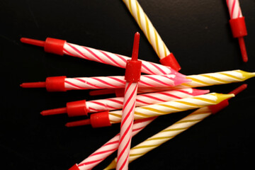 Candles for the cake are scattered on the black table. Dimmed lights.