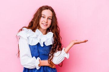 Little caucasian girl isolated on pink background showing a copy space on a palm and holding...