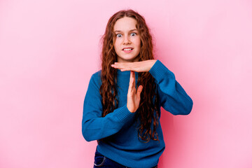 Little caucasian girl isolated on pink background showing a timeout gesture.