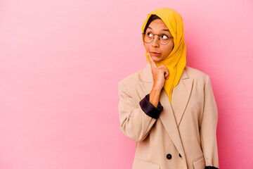 Young business muslim woman isolated on pink background looking sideways with doubtful and...