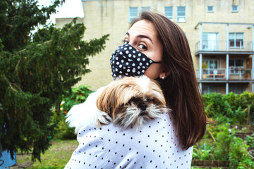 Brunette girl wearing a facemask and holding her cute shihtzu dog